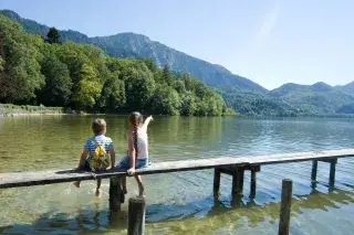 Zwei Kinder sitzen auf einem Steg am Kochelsee