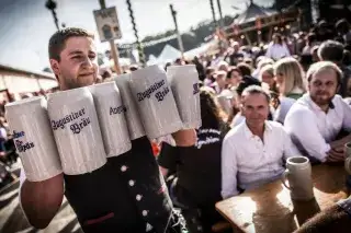 Bedienung trägt Steinkrüge mit Bier auf der Oidn Wiesn