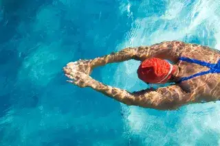 Eine Schwimmerin im Hallenbad zieht ihre Bahnen