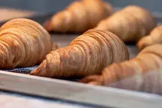 Frisch gebackene Croissants auf einem Backblech.