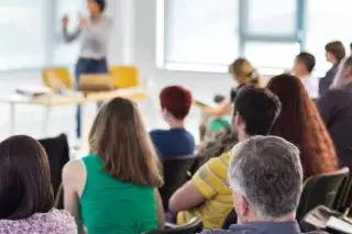 Erwachsene lauschen einem Weiterbildungsseminar