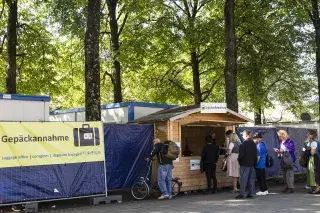 Besucher der Wiesn geben ihr Gepäck bei der Gepäckaufbewahrung ab