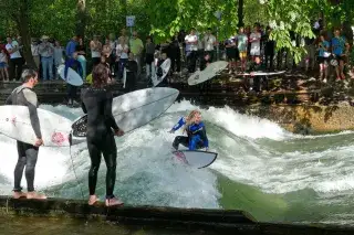 Eine Surferin reitet die Eisbachwelle im Lehel