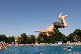 Ein Junge springt vom Startblock ins Schwimmerbecken des Schyrenbads