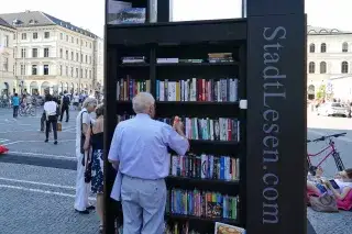 Ein Mann steht vor dem StadtLesen Bücherregal am Odeonsplatz.