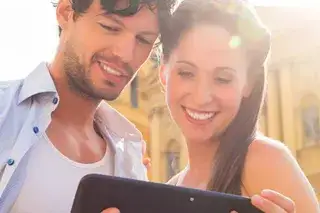 Ein Mann und eine Frau stehen vor der Theatinerkirche und schauen auf ein Tablet