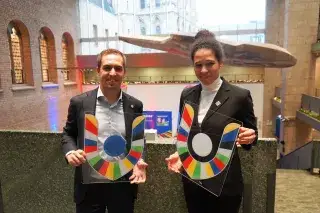 Philipp Lahm and Celia Sasic in suits holding the volunteer logo in their hands