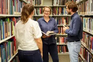 Drei Personen unterhalten sich in der Bibliothek