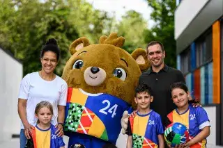 Celia Sasic, Philipp Lahm, EM-Maskottchen Albärt und Kinder posieren an einer Schule für ein Foto