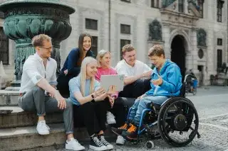 Junge Menschen am Marienplatz in München schauen auf einen Laptop