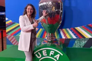 Kathrin Lehmann touches a big version of the UEFA EURO 2024 trophy and smiles