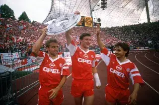 Hansi Flick, Alan McInally and Olaf Thon raise the championship trophy in the Olympic Stadium