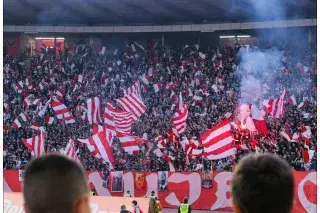 Fans at the Red Star Belgrade stadium waving red and white flags