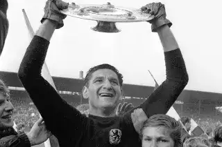 Old photo of goalkeeper Petar Radenkovic jubilantly raising the championship trophy in the air for 1860 Munich