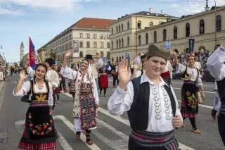 People in colorful Serbian costumes walk along Munich's Ludwigstraße