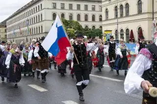 Mann mit slowenischer Flagge in der Hand und traditioneller Tracht läuft auf der Münchner Ludwigstraße