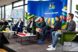 Die Teilnehmer der Pressekonferenz im Olympiapark sitzen auf der Bühne und stellen das EM-Rahmenprogramm vor.