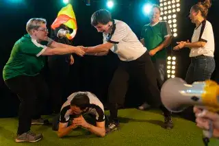 Scene from an improvisational theater performance with participants in soccer jerseys