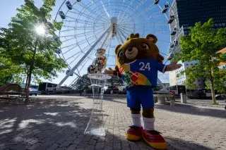 Die EM-Trophäe in München mit Maskottchen Albärt vor dem Umadum-Riesenrad