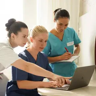 Pflegerinnen schauen auf Laptop