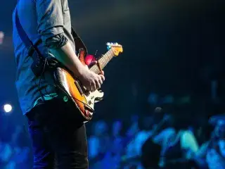 Musiker mit E-Gitarre bei einem Konzert auf der Bühne